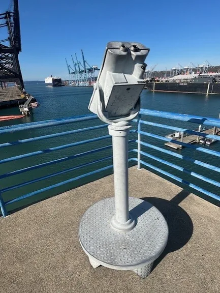 Public viewing binoculars overlooking ships and cranes at the Port of Tacoma.